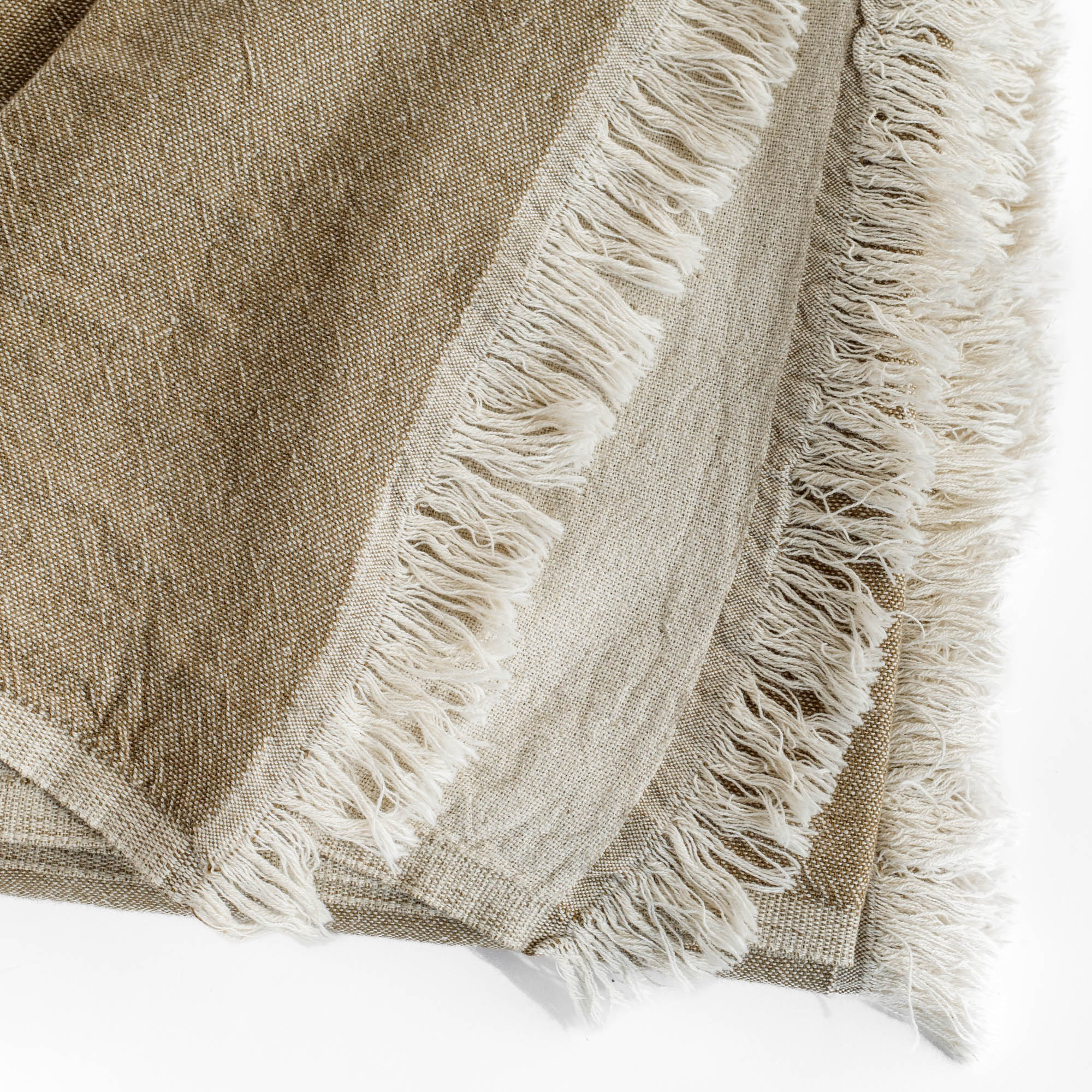 a reversible light brown and natural linen cotton throw blanket with a delicate fringe edge : close up view