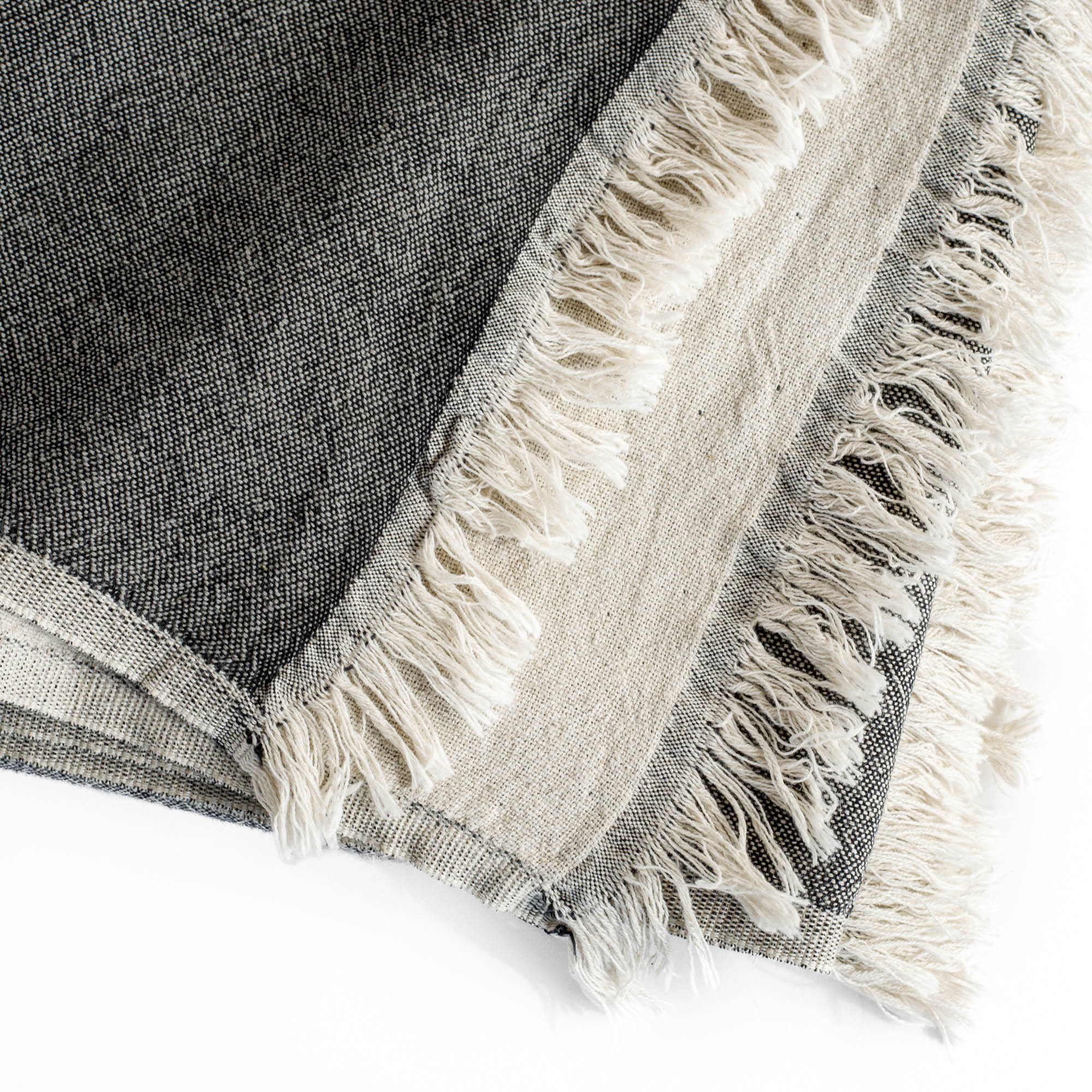 a charcoal gray and natural linen cotton throw blanket with a delicate fringe edge : close up view