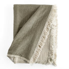 Alba Throw Blanket Olive, a reversible olive green and natural linen cotton throw blanket with a delicate fringe edge from Tonic Living