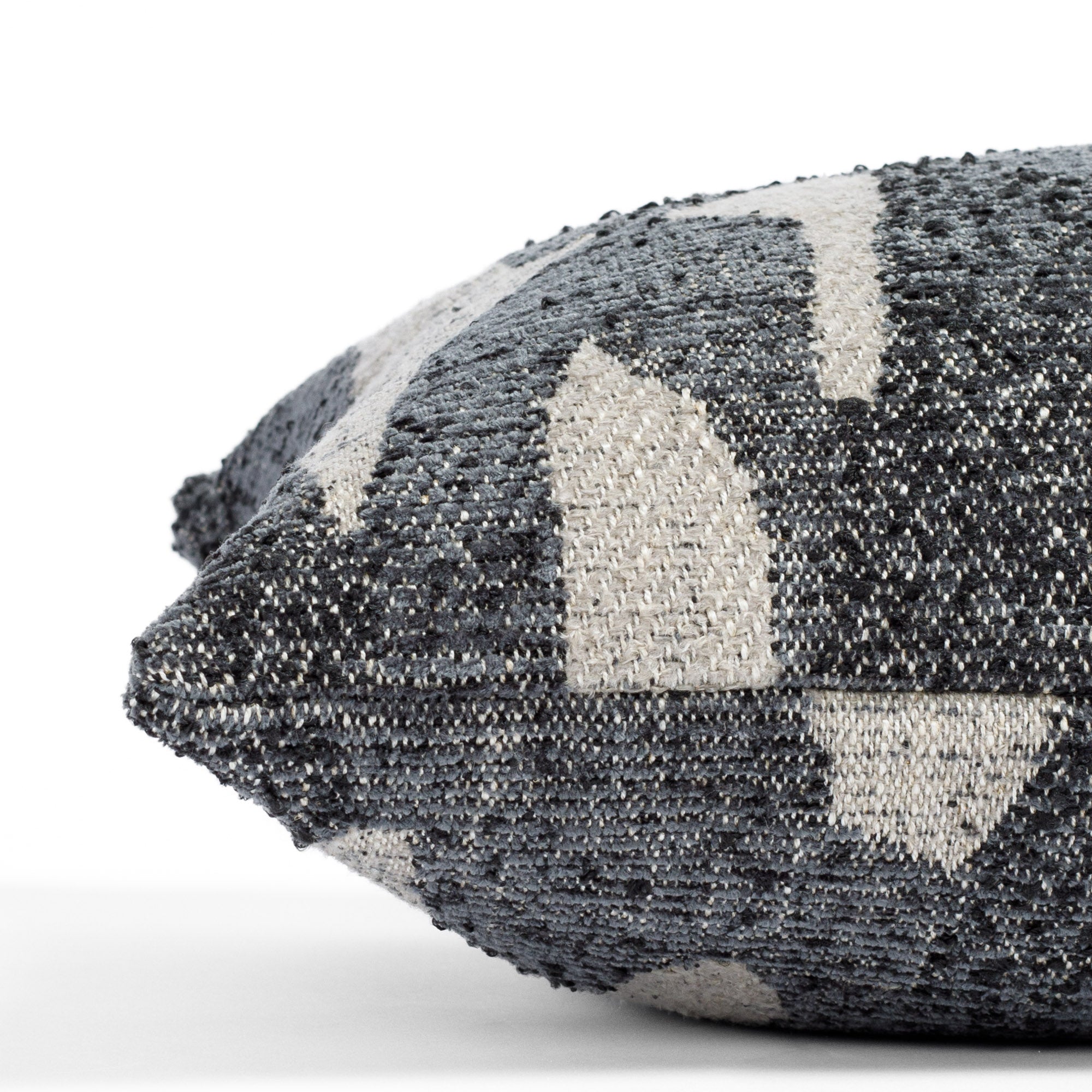 a denim blue and earthy grey organic abstract patterned lumbar pillow : close up side view