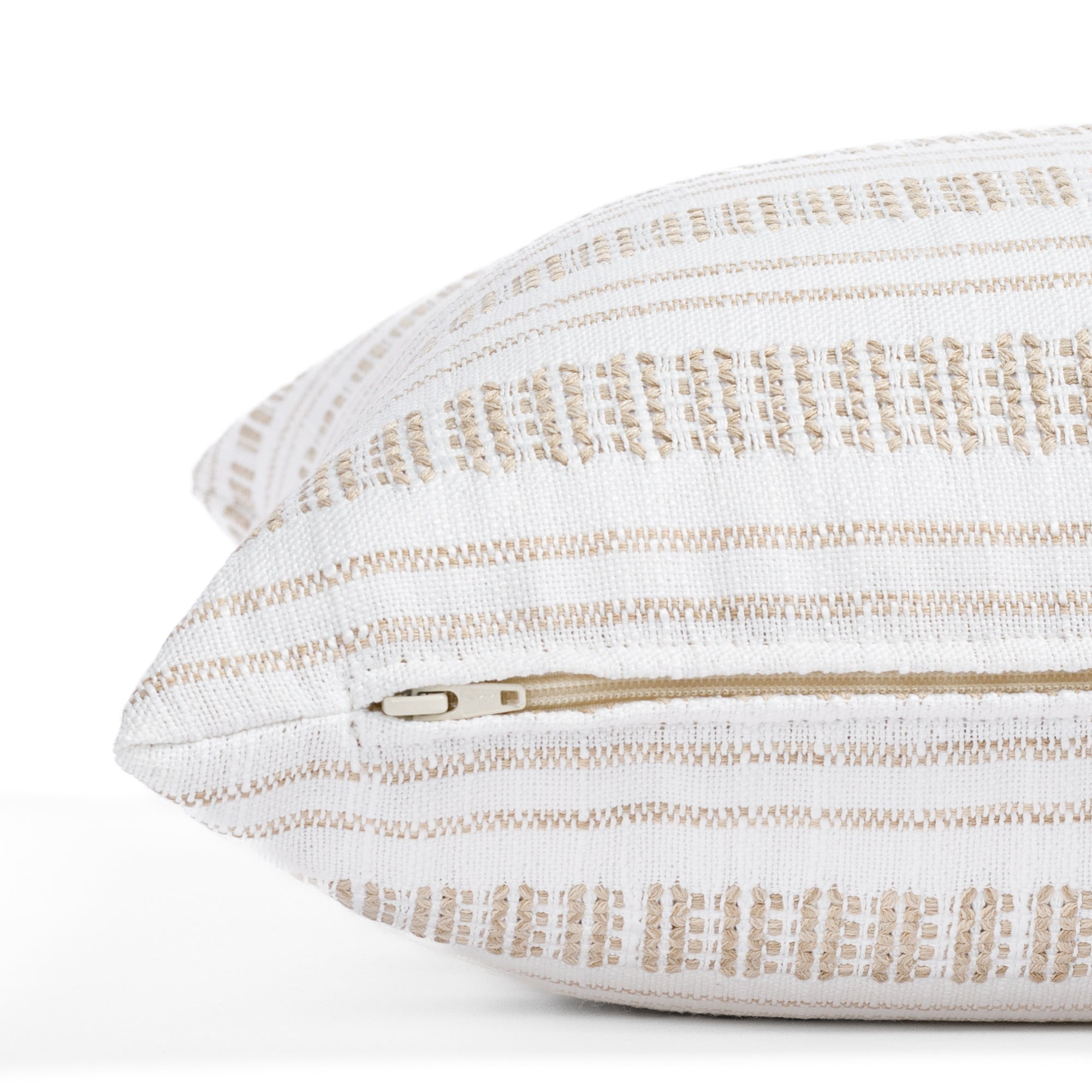 a white and tan striped throw pillow - close up zipper view