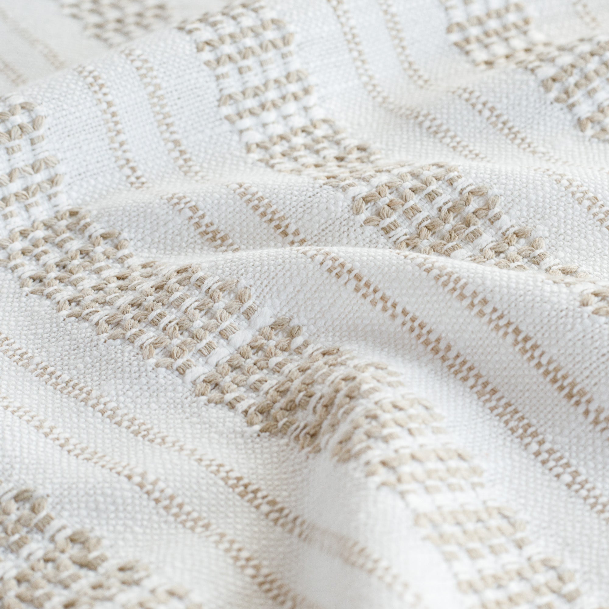 a white and tan intricate woven striped fabric - close up view