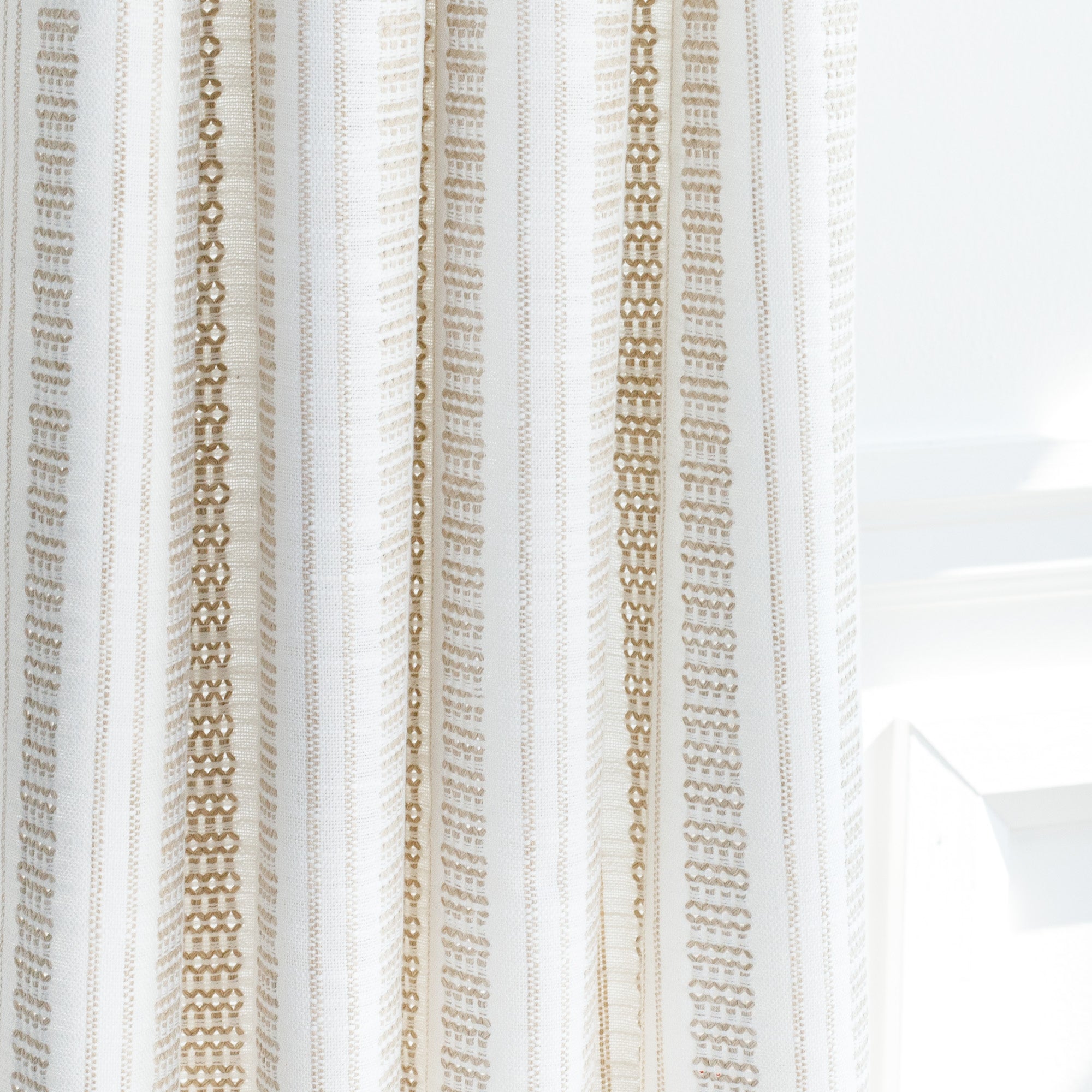 a white and beige woven stripe patterned curtain fabric : close up view