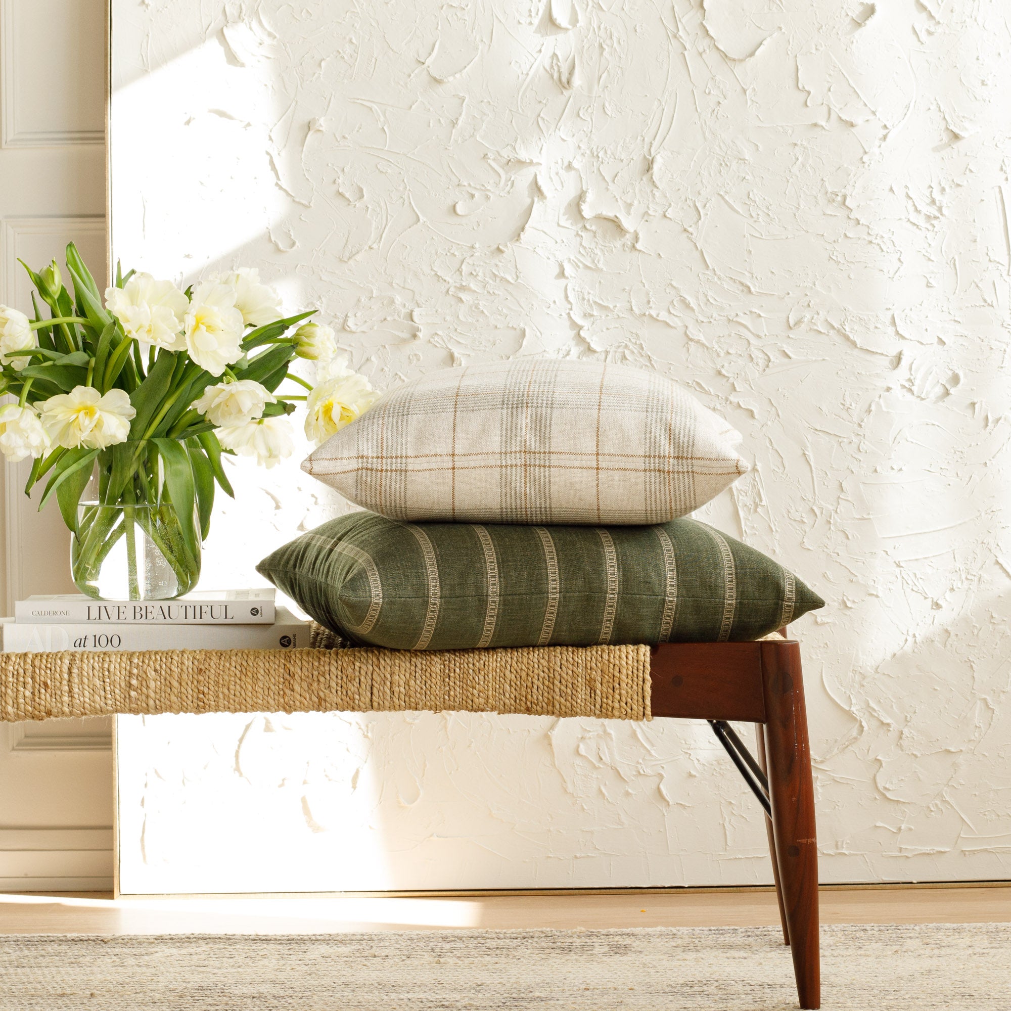 Neutral and green designer pillows from Tonic Living, styled on a bench.