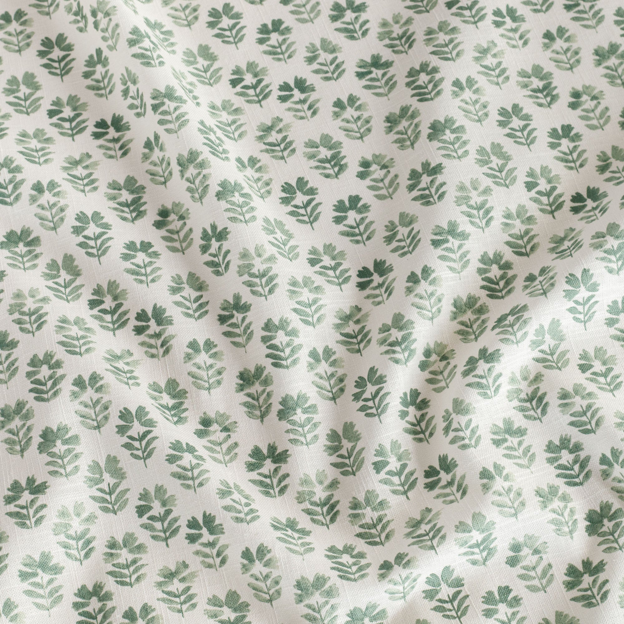 A warm white linen-blend fabric with green flowers, a home decor fabric from Tonic Living.