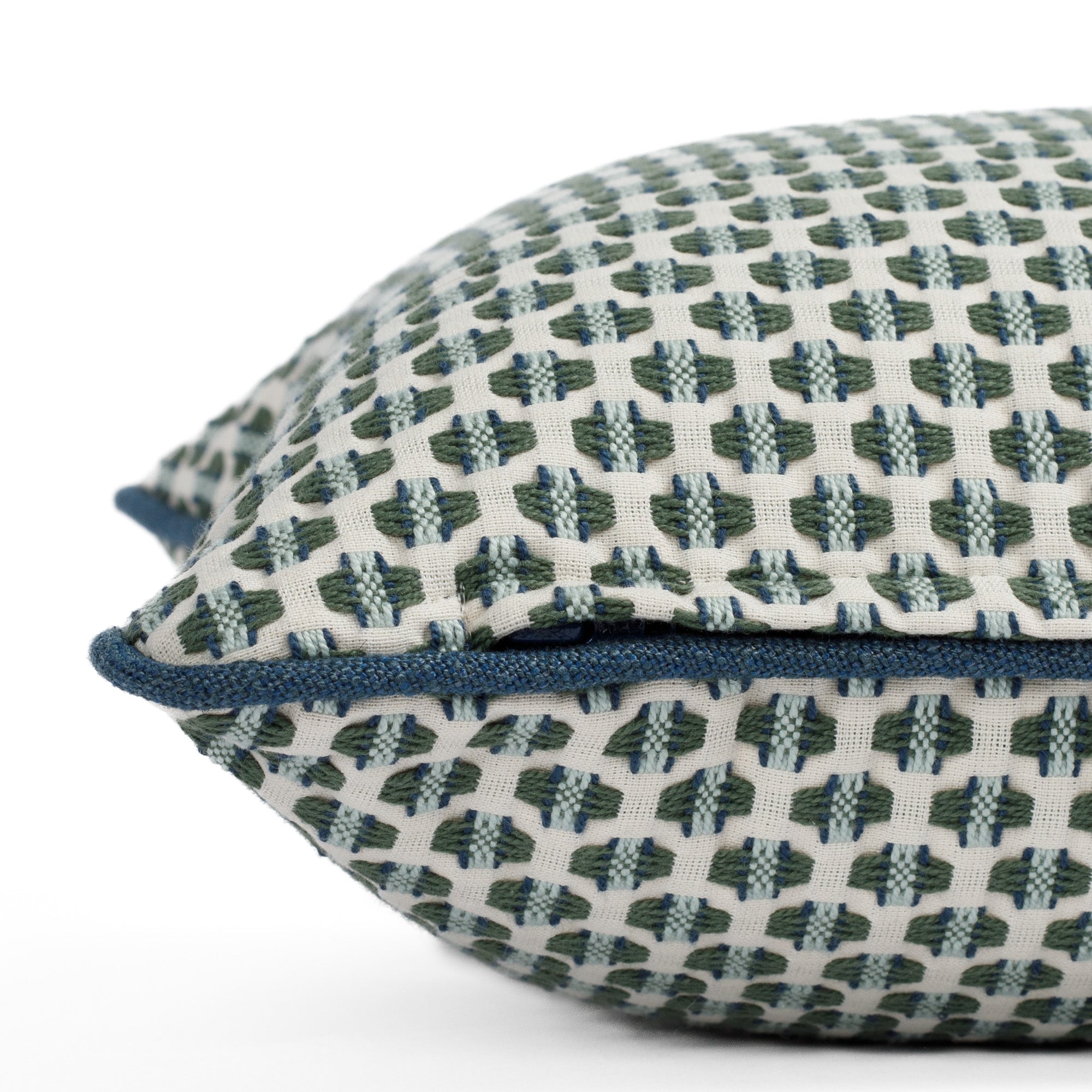 A white, green, light blue and denim blue pillow with piping: close up zipper view.