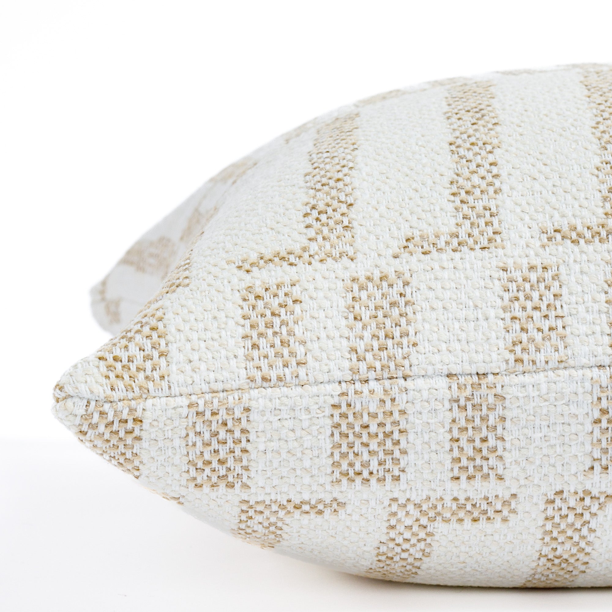 a white and beige graphic organic geometric patterned outdoor throw pillow : close up side view