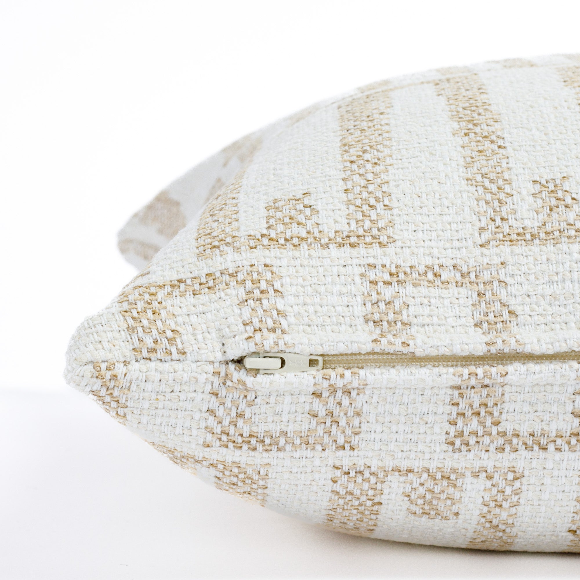 a white and beige graphic organic geometric patterned outdoor throw pillow : close up zipper view