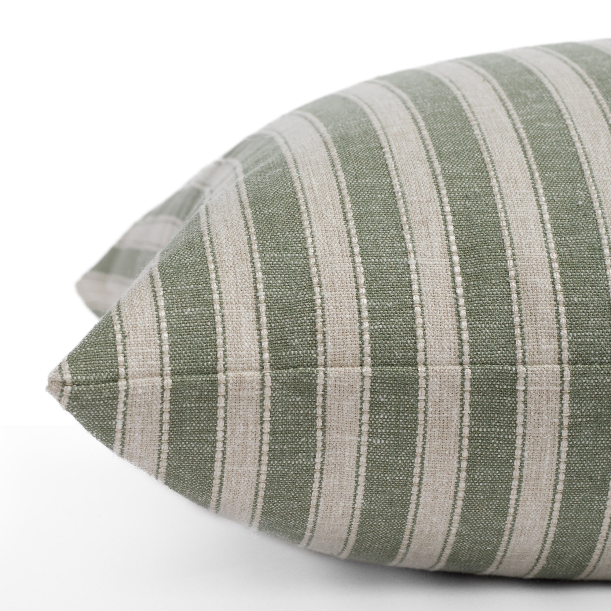 A green and beige striped toss pillow: close up side view.