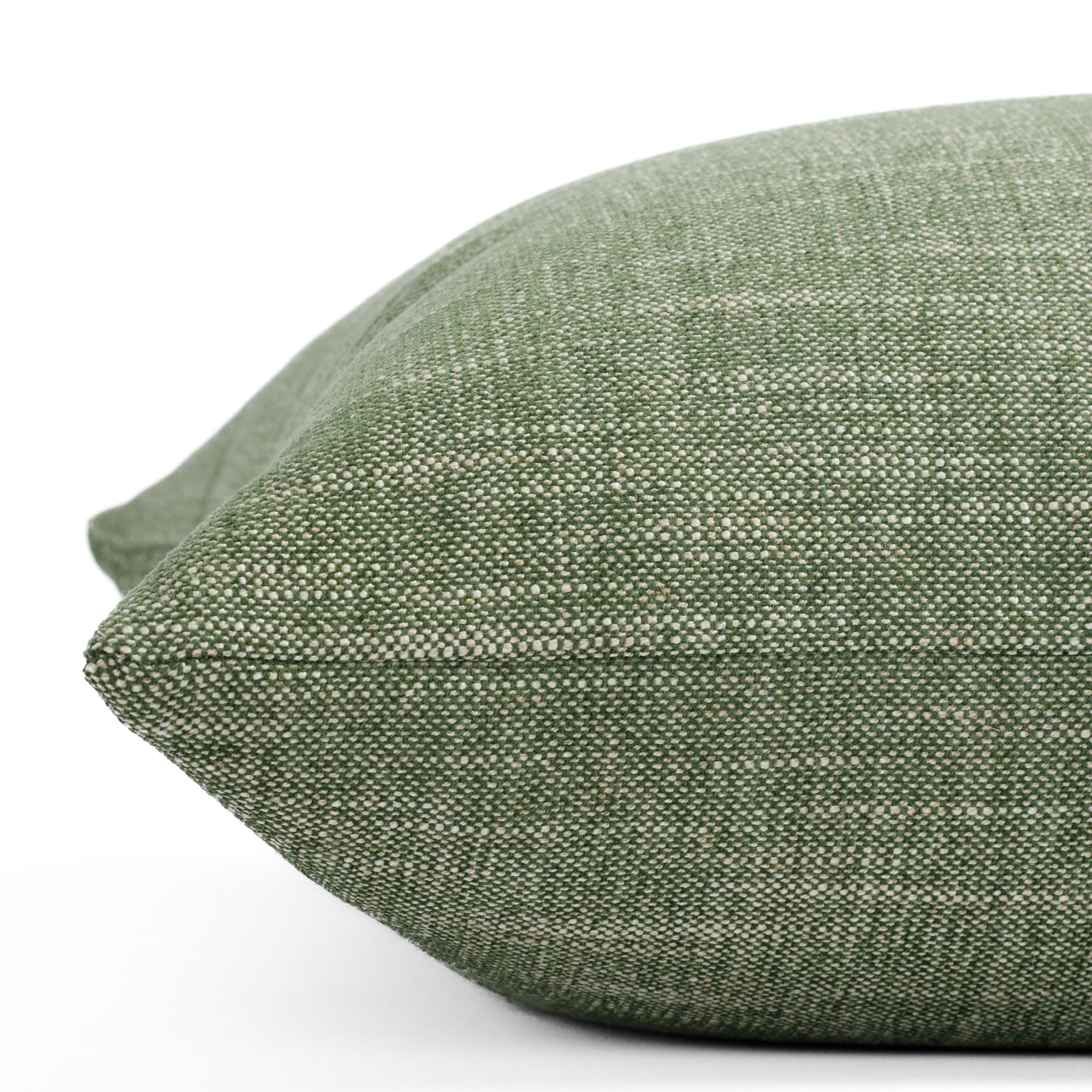 A medium green and beige solid textured pillow: close up side view.